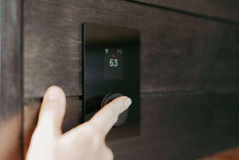 A hand adjusting a wall thermostat